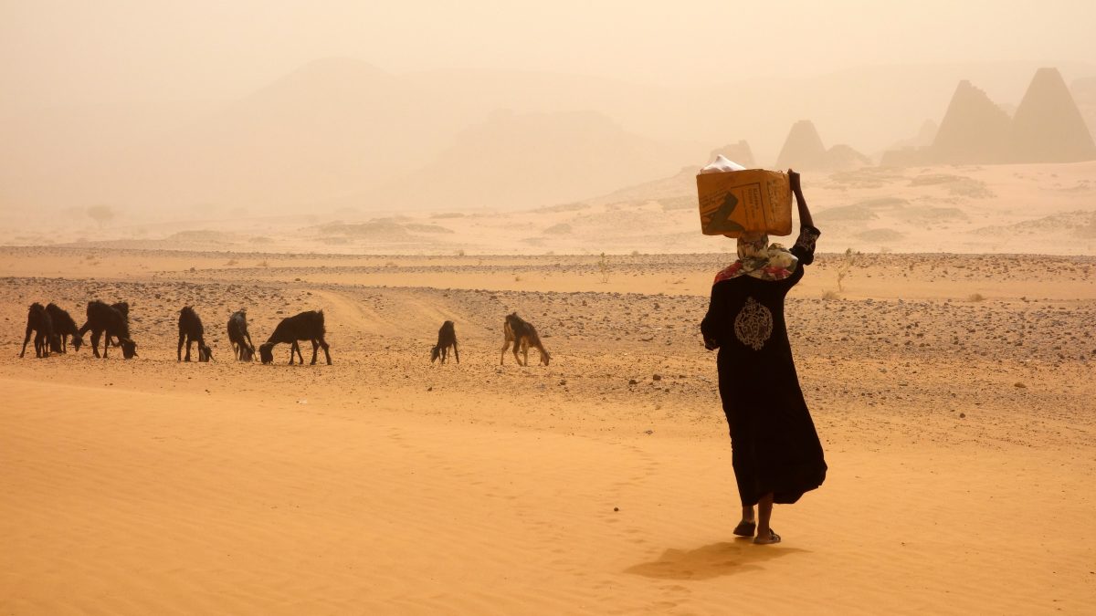Une femme au Soudan marche sous une tempête de sable.