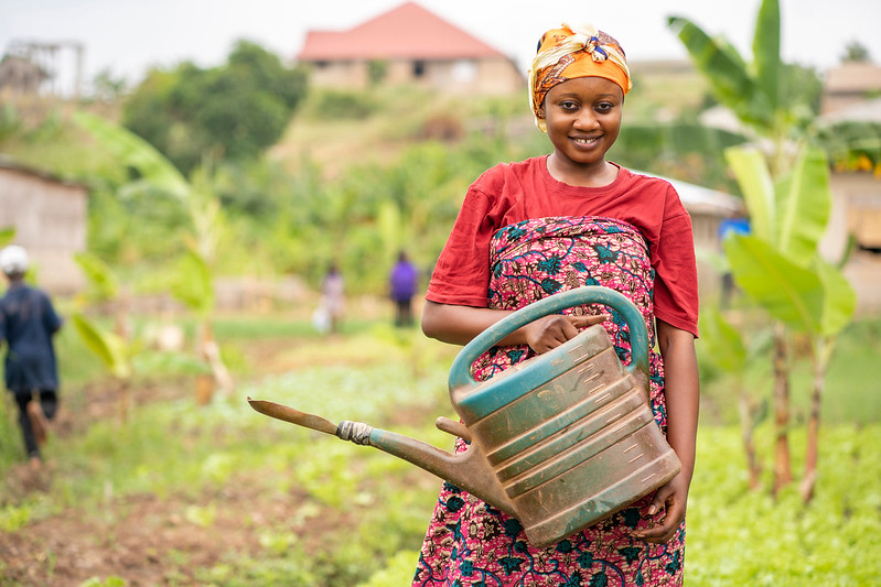 African women holding a watering can and smiling at the camera